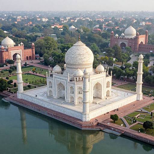 Aerial photograph of the Taj Mahal, an iconic white marble mausoleum with four minarets, surrounded by lush greenery and red