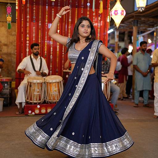 Photograph of a South Asian woman in a navy blue saree with silver embroidery, dancing in a vibrant, colorful street festival, musicians playing drums in
