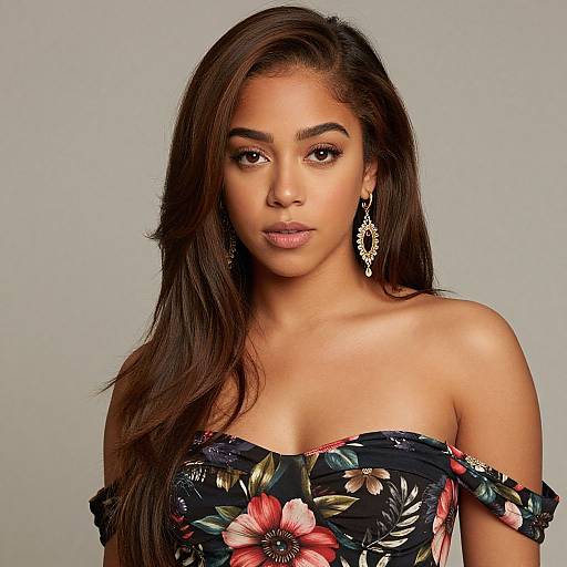 Photograph of a young woman with long brown hair, wearing an off-shoulder floral dress and elegant drop earrings, against a plain gray background.