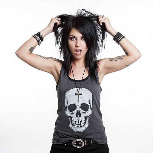 Photograph of a punk-rock style woman with black hair, skull tank top, black bracelets, tattoos, and belt, pulling hair up.