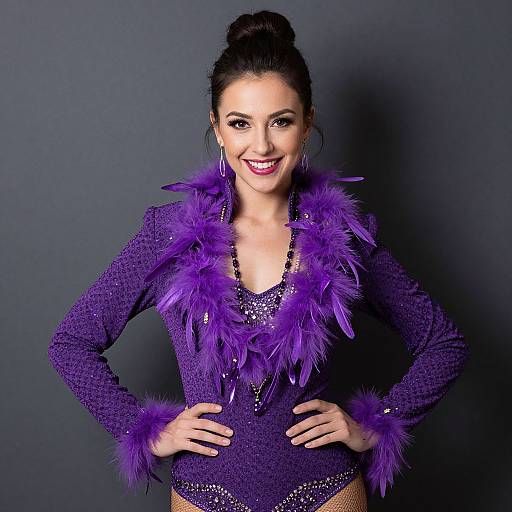 Photograph of a smiling woman with dark hair in an updo, wearing a sparkling purple leotard with purple feather accents, against a dark gray