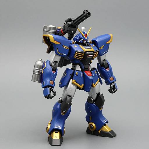 Photograph of a detailed, blue and yellow robotic mecha with silver accents, large cannon arm, and red chest panel, standing on a plain gray