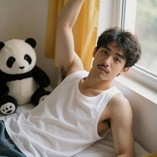 Young man in white tank top lying on bed