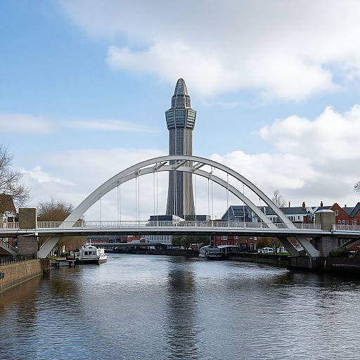 Photograph of a white arch bridge spanning a river, with a tall, cylindrical tower centered in the background under a blue, cloudy sky.