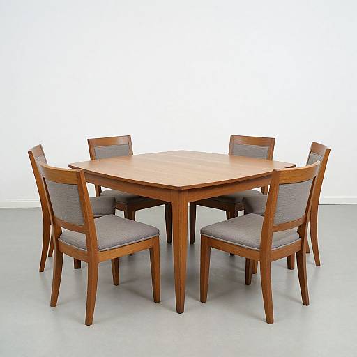 Photograph of a wooden, hexagonal dining table with six matching chairs, featuring gray fabric seats, set against a plain white background.