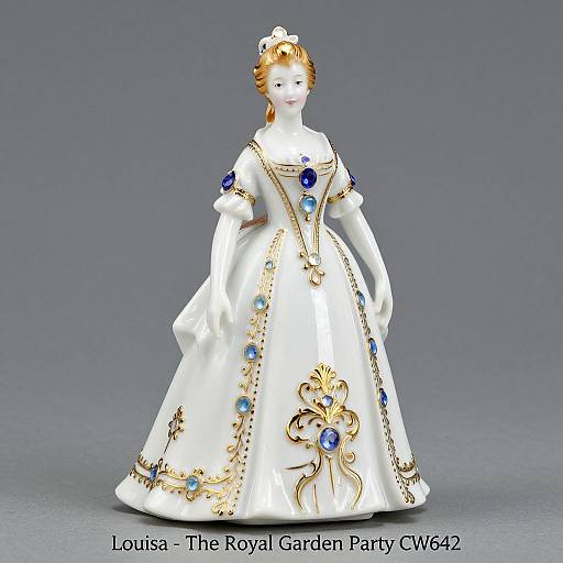 Photograph of a porcelain doll wearing an ornate white gown adorned with blue and gold accents, standing against a gray background. Text reads 