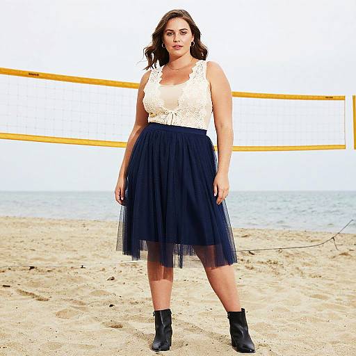 Photograph of a curvy woman with medium skin tone, brown wavy hair, wearing a white lace top and navy blue tulle skirt, black