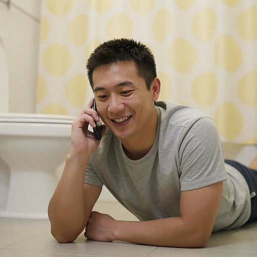 Smiling Man on Bathroom Floor with Phone