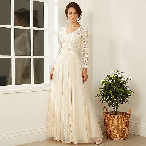 Photograph of a woman with dark hair in a white lace long-sleeve dress and flowing skirt, standing by a window with a potted plant