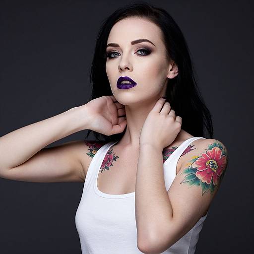 Photograph of a pale-skinned woman with black hair, dark purple lipstick, white tank top, and vibrant red flower tattoo on her shoulder, against