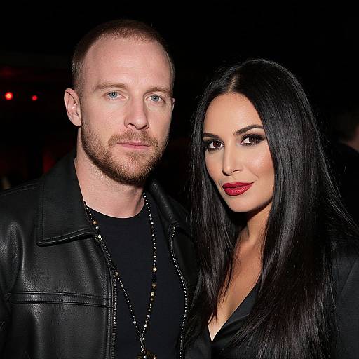 Photograph of a bearded, fair-skinned man in a black leather jacket standing beside a dark-haired, olive-skinned woman with red lipstick,
