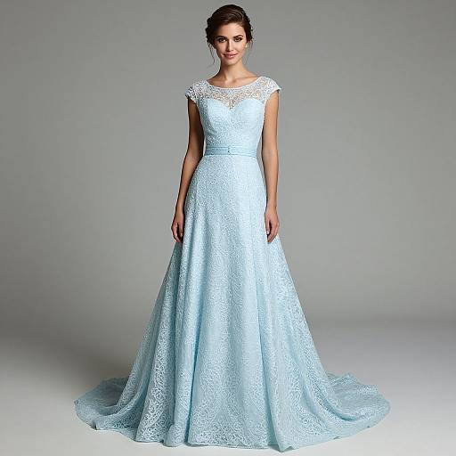 Photograph of a smiling woman in a light blue, lace, sleeveless, floor-length wedding gown with a modest train, standing against a plain gray