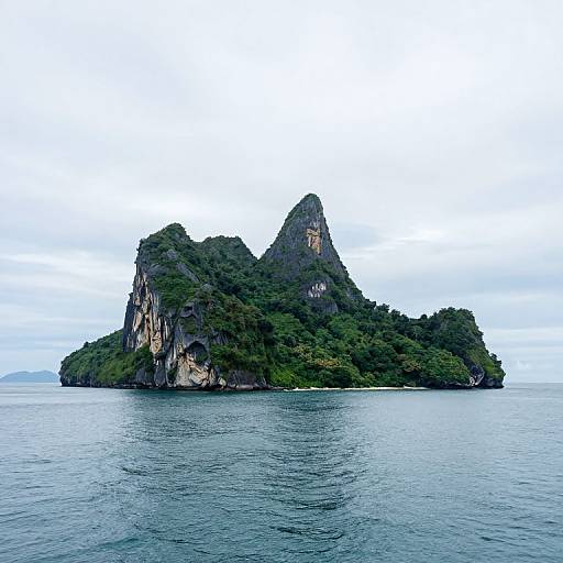 Photograph of a small, lush, green island with two prominent rocky peaks rising from calm, blue ocean under a cloudy sky.