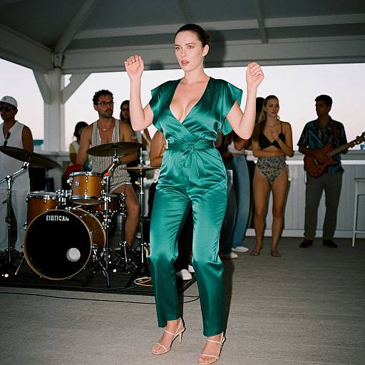 Photograph of a woman in a deep green satin jumpsuit with a plunging neckline, dancing in front of a live band under a white tent.
