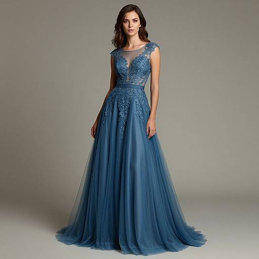 Photograph of a woman with dark brown hair in a floor-length, blue, sleeveless gown with intricate lace and sheer detailing, standing against a gray