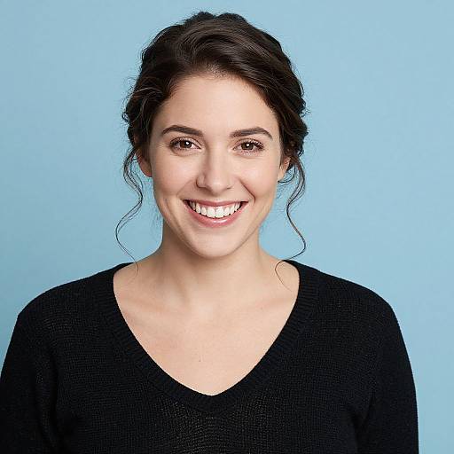 Photograph of a smiling young woman with fair skin, dark brown hair in a loose updo, wearing a black V-neck sweater, against a light