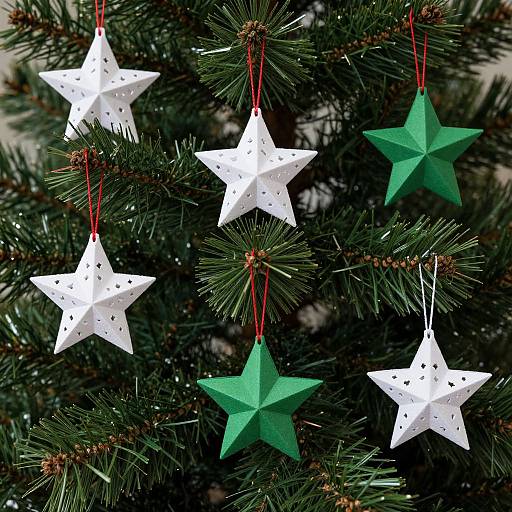 Photograph of a Christmas tree adorned with five paper stars; three white with red strings and two green with red strings.