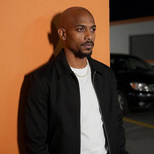 Stylish man against orange wall at night