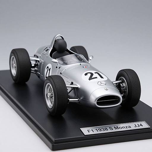 Photograph of a silver 1938 Monaco Grand Prix race car on a black display base, numbered 23, with detailed textures and realistic lighting.