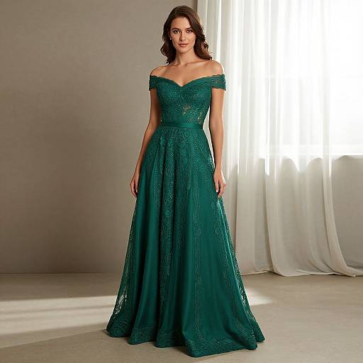 Photograph of a brunette woman in an off-shoulder, emerald green lace gown with a full skirt, standing in a sunlit room with