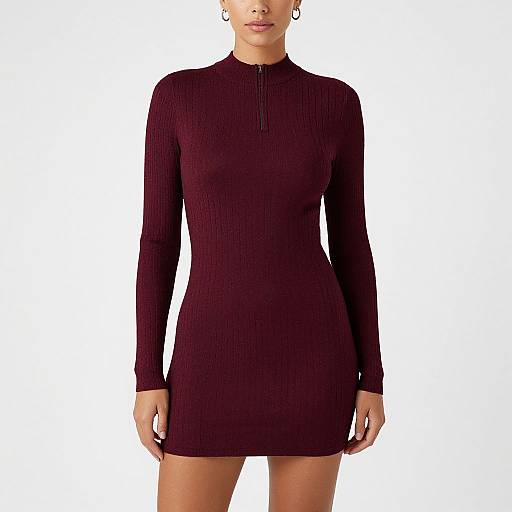 Photograph of a woman in a form-fitting, long-sleeved, ribbed, burgundy mini dress with a high neckline, standing against