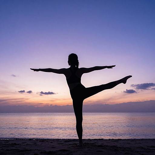 Silhouetted female dancer in a one-legged pose against a vibrant sunset over a calm ocean, with purple and orange sky. Photograph.