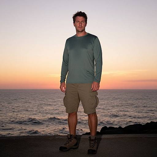 Photograph of a Caucasian man with short, spiked brown hair, wearing a teal long-sleeve shirt, khaki cargo shorts, and black sneakers