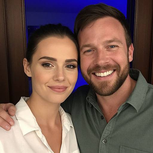 Photograph of a smiling couple: a fair-skinned woman with dark hair in a white blouse and a fair-skinned bearded man in a green