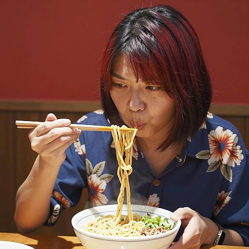 Asian Woman Enjoying Noodles in Restaurant