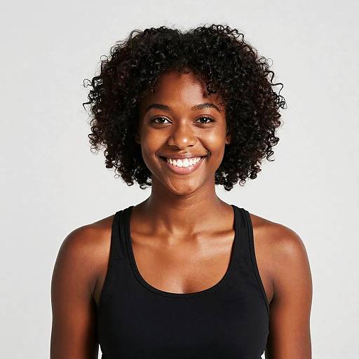 Photograph of a smiling Black woman with curly hair, wearing a black tank top, against a white background.