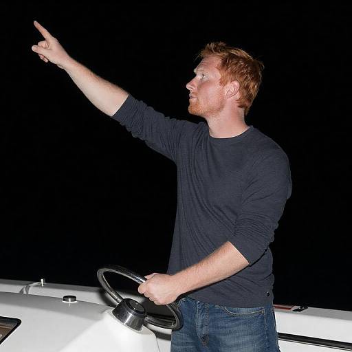 Man Steering Boat and Pointing at Night