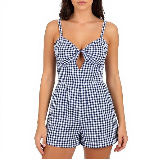 Photograph of a woman with long dark hair wearing a blue and white gingham romper with a keyhole cutout, standing against a plain white