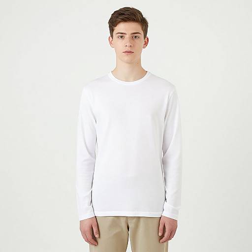 Photograph of a young Caucasian man with short brown hair, wearing a plain white long-sleeve shirt and beige pants, standing against a white background