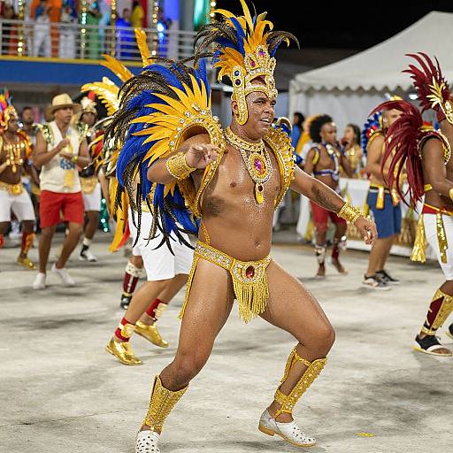 Photograph of a muscular Black man in vibrant Carnival costume, adorned with gold jewelry, blue and yellow feather headdress, and loincloth, dancing