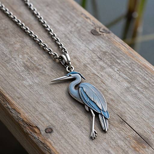 Photograph of a silver necklace with a detailed, engraved bird pendant, resting on a weathered wooden surface.