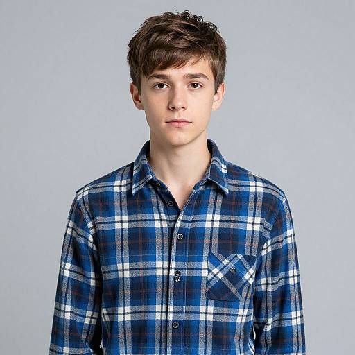 Photograph of a young white male with short brown hair, wearing a blue and white plaid button-up shirt, against a light blue background.