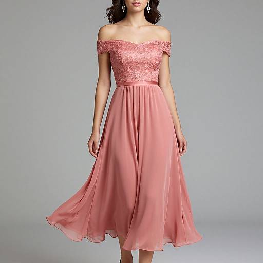 Photograph of a woman in an off-shoulder, lace-trimmed pink dress with a flowing, chiffon skirt, standing against a plain