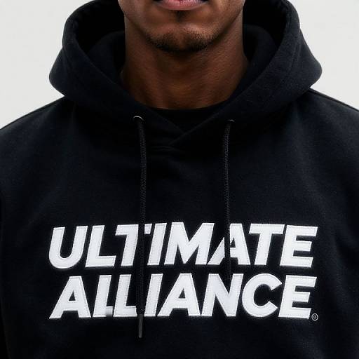 Photograph of a dark-skinned man from the chin to chest, wearing a black hoodie with bold white text 