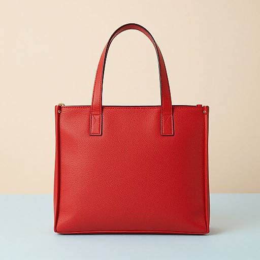 Photograph of a vibrant red, textured leather handbag with two sturdy handles, set against a plain beige background and light blue surface.