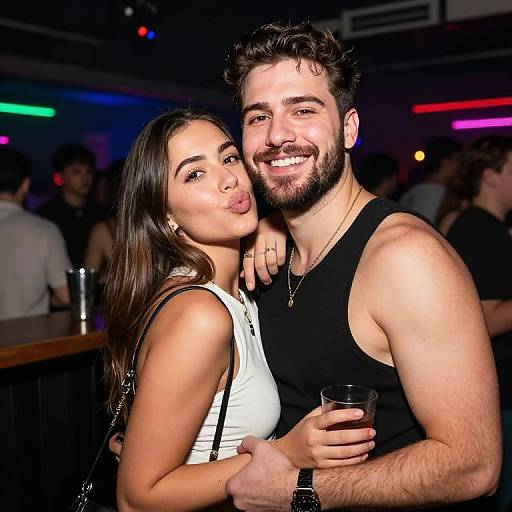 Photograph of a smiling, bearded man in a black tank top and a young woman with long brown hair in a white sleeveless top, posing