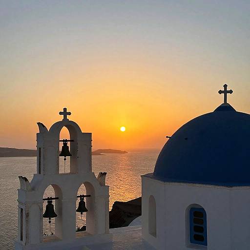 Photograph of a Greek island sunset with a white bell tower and blue-domed church, silhouetted against a vibrant orange sky.