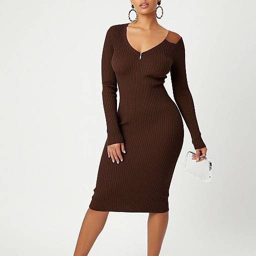 Photograph of a woman in a form-fitting, long-sleeve, black ribbed dress with a V-neck and cut-out shoulder, holding