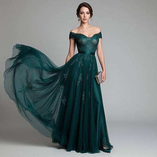 Photograph of a woman in an off-the-shoulder, dark teal, lace-embellished, floor-length gown with a flowing chiffon