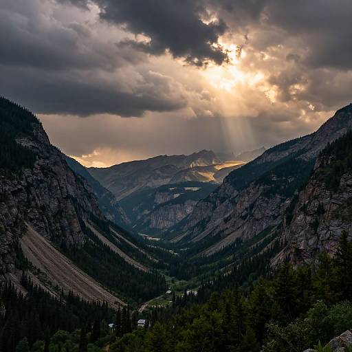 Photograph of a dramatic mountain valley at sunset, with sun rays piercing dark clouds, illuminating jagged peaks and dense evergreen forests.