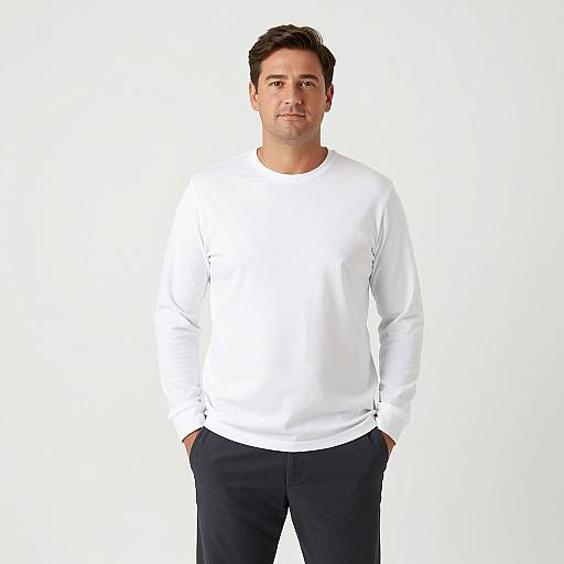 Photograph of a medium-build man with short dark hair, wearing a white long-sleeve shirt and black pants, standing against a plain white background