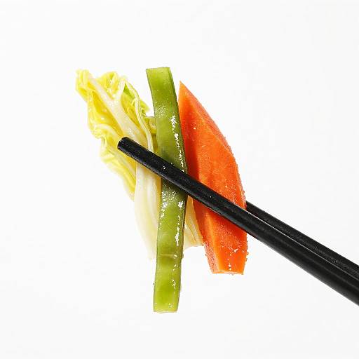 Photograph of black chopsticks holding slices of green celery, yellow lettuce, and red tomato on a white background.