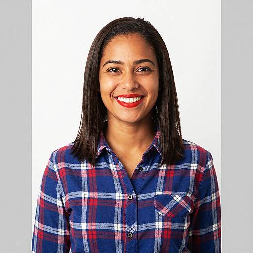 Photograph of a smiling woman with dark straight hair, wearing a red, white, and blue plaid shirt, against a plain white background.