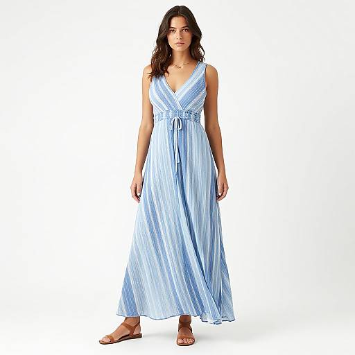 Photograph of a young woman with wavy brown hair, wearing a light blue, sleeveless, V-neck maxi dress with vertical stripes, and brown