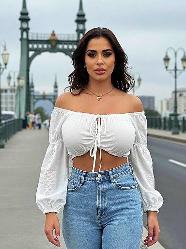 Photograph of a confident woman with long black hair, wearing a white off-the-shoulder crop top and high-waisted blue jeans, standing