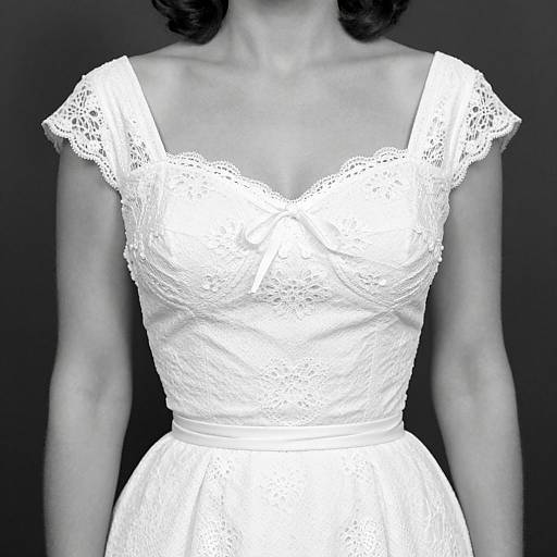 Black-and-white photograph of a woman's upper body in a white, lace, off-shoulder wedding dress, showcasing delicate floral patterns and a fitted